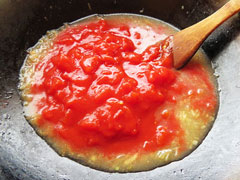 フライパンにトマト缶を入れる