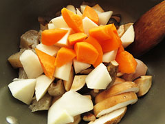 鶏もも肉を炒めている鍋に、里芋とほうれん草以外の切り分けた野菜を入れる