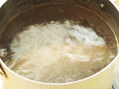 沸騰した湯に豚肩ブロック肉を入れて下茹でする。