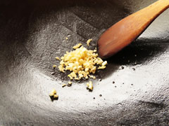米を炒めた中華鍋に、ごま油小さじ1/2とにんにくを入れる。