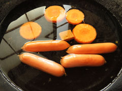 フライパンに水とコンソメキューブ、スープ用に切り分けたにんじんとソーセージを入れる。