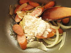 ソーセージと玉ねぎを炒めている鍋に薄力粉を加える。