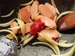 魚肉ソーセージを炒めているフライパンに、ケチャップと醤油を加える。