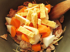 豚肉を炒めている鍋に大根とにんじん、油揚げを入れる。