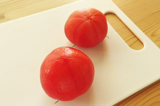 まな板に乗った、湯むきトマト2個。