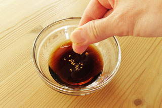 めんつゆとごま油の入った小皿に、白ごまを指ですりつぶしながら加える。