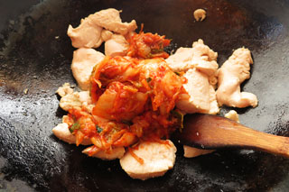 炒めている鶏むね肉にキムチをくわえる。